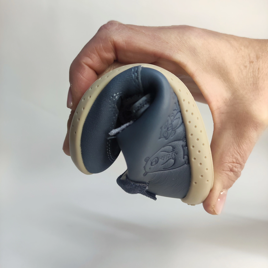 Detalle de calzado barefoot bebé niño color azul doblado para mostrar su extrema flexibilidad y suela blanda.